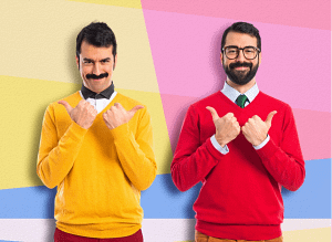 Deux hommes souriants, l’un en pull jaune, l’autre en pull rouge, pointant chacun leurs pouces vers eux-mêmes sur un fond coloré.